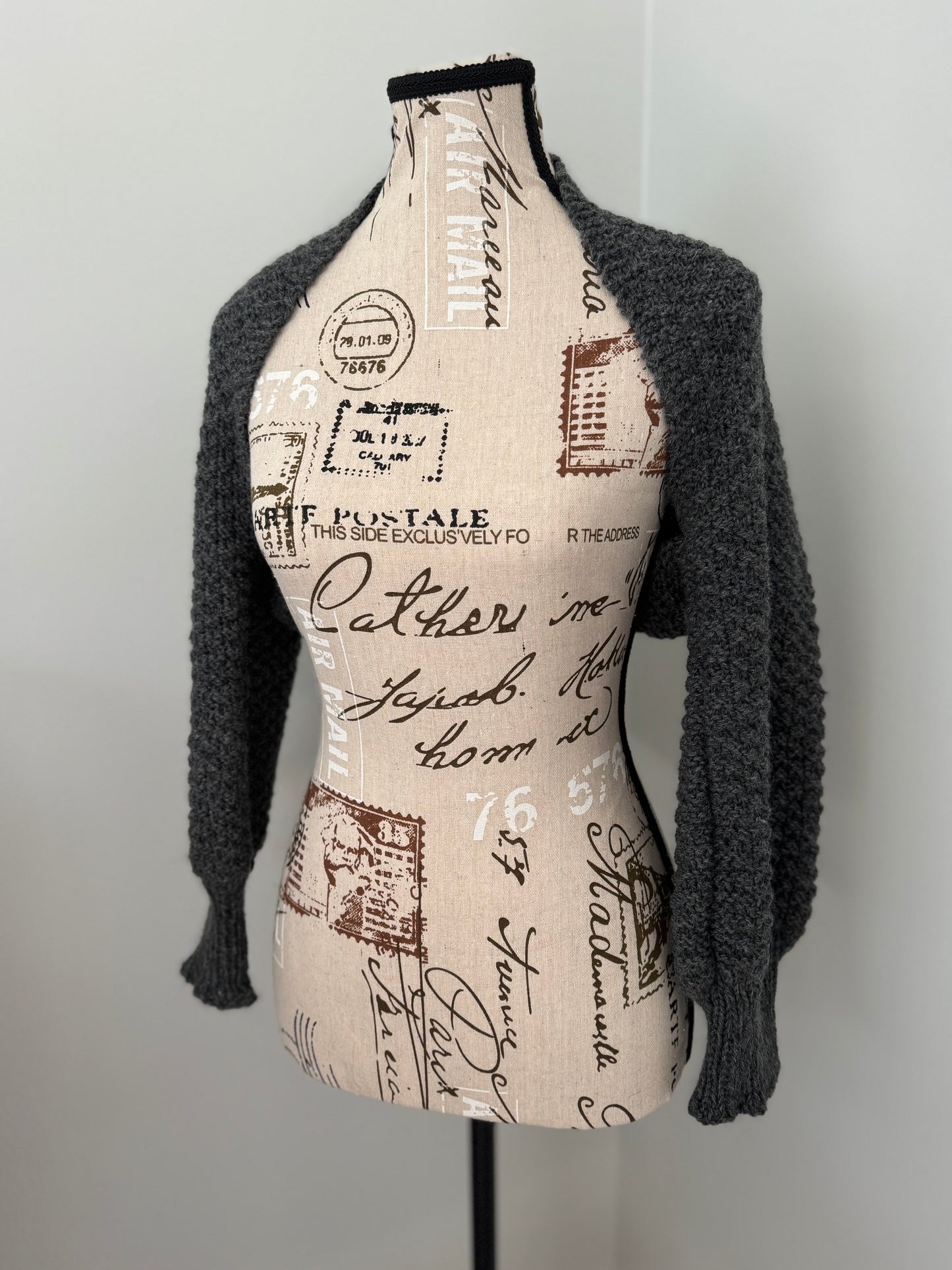 Hand-knitted shrug featuring double moss stitch and prominent cuffs. Custom commission in a color of your choice.