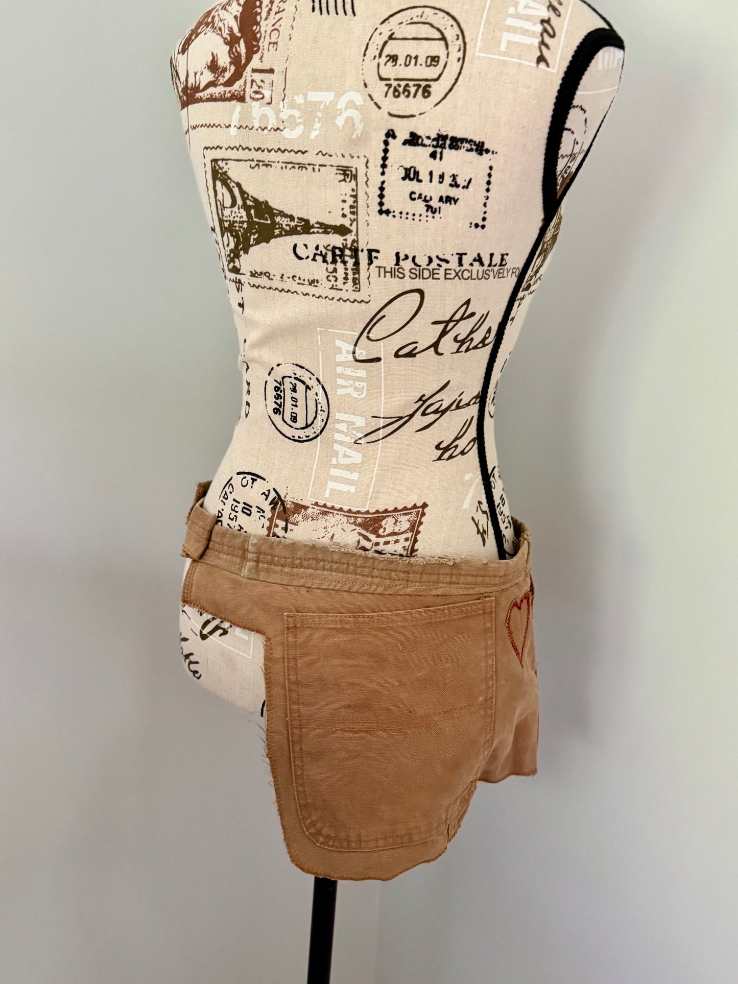 Durable golden brown festival bag repurposed from a pair of bib overalls and features a hand stitched heart patch, original pockets and fasteners. Designed for utility and to carry necessities such as phone, keys, wallet, etc.
