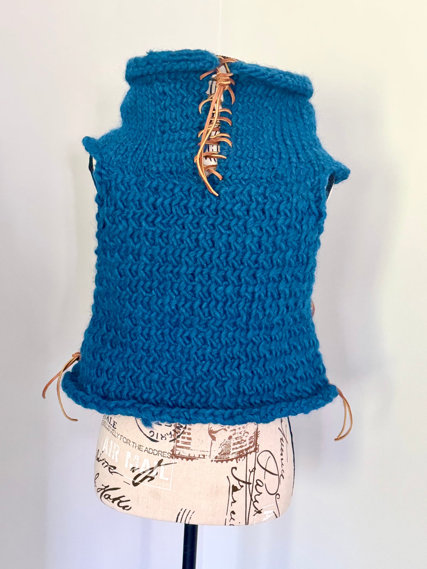 Super bulky and structured hand knitted vest constructed in a herringbone stitch featuring leather lace accents. Custom commission this piece in the color of your choice and in cropped or regular length.