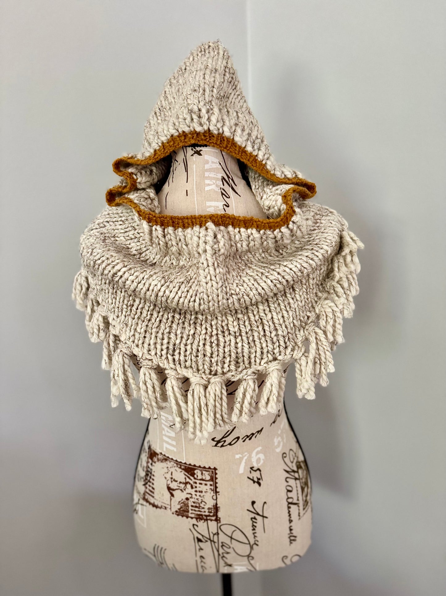 Beige hooded bandana cowl featuring fringe edging and gold accents.