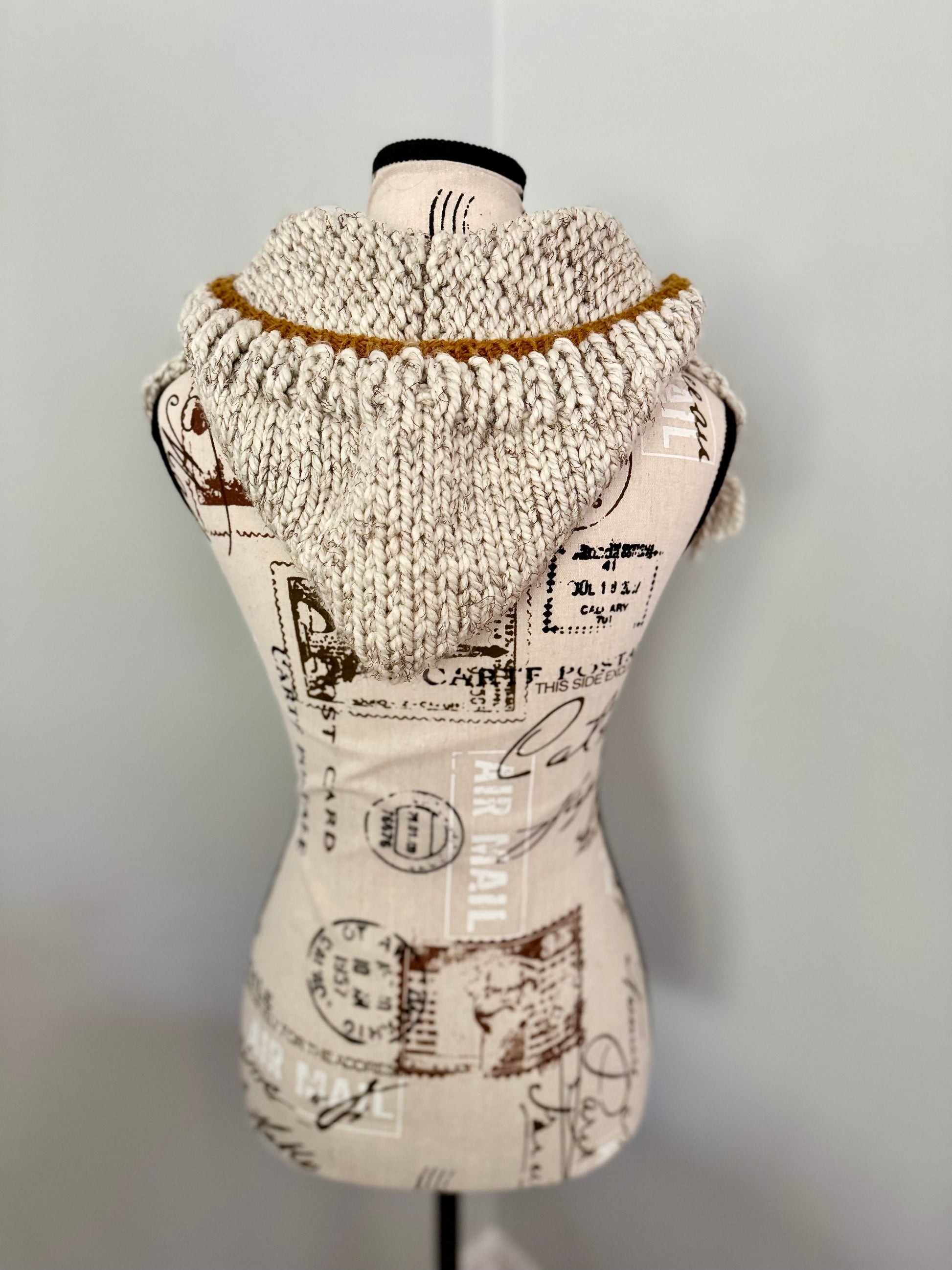 Beige hooded bandana cowl featuring fringe edging and gold accents.