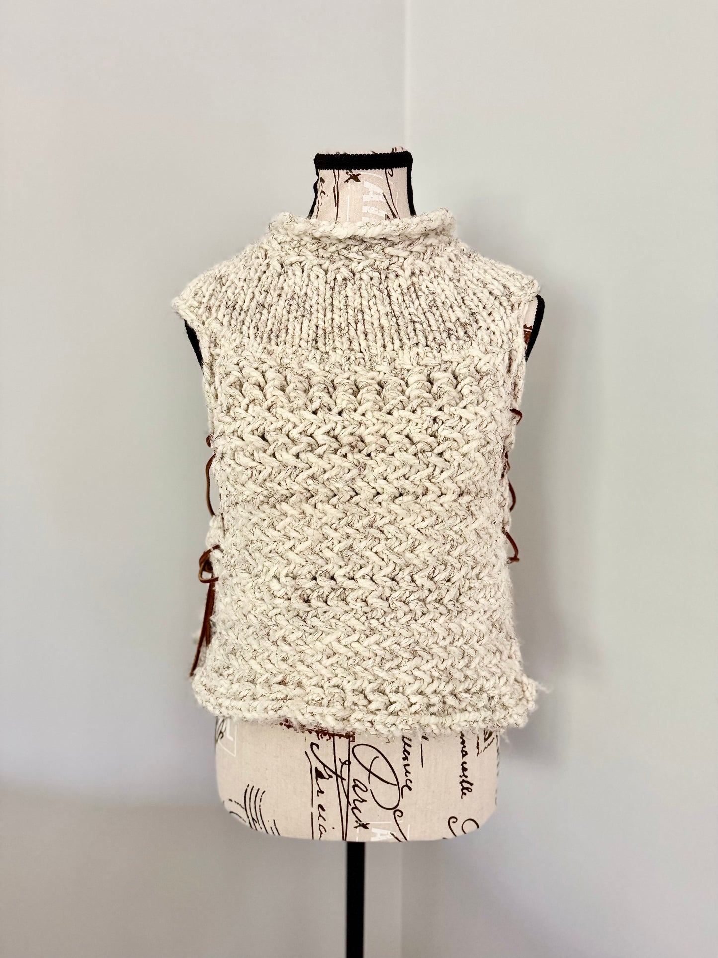 Super bulky and structured hand knitted vest constructed in a herringbone stitch featuring leather lace accents. Custom commission this piece in the color of your choice and in cropped or regular length.