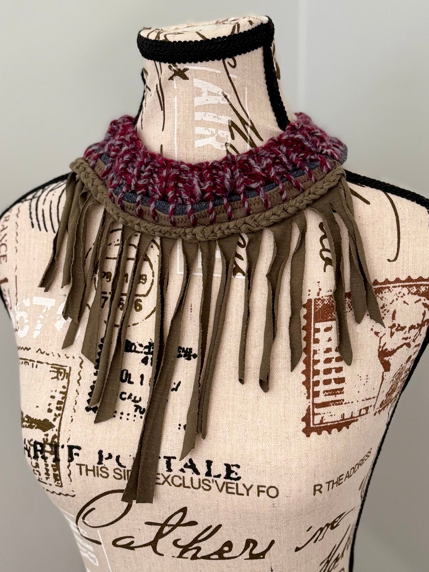Upcycled from an army green t-shirt this necklace repurposes the t-shirt collar and features a variagated plum hand stitched ribbed neckline and crochet chain accent.