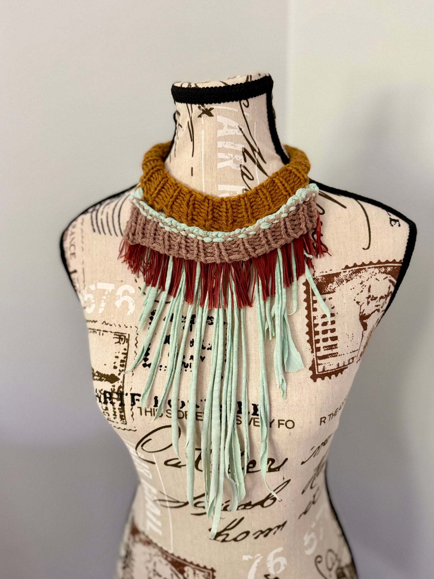 Upcycled from a teal green t-shirt this  dramatic fringed necklace repurposes the t-shirt collar and features a gold and tan layered hand stitched ribbed neckline and chainnette fringe.