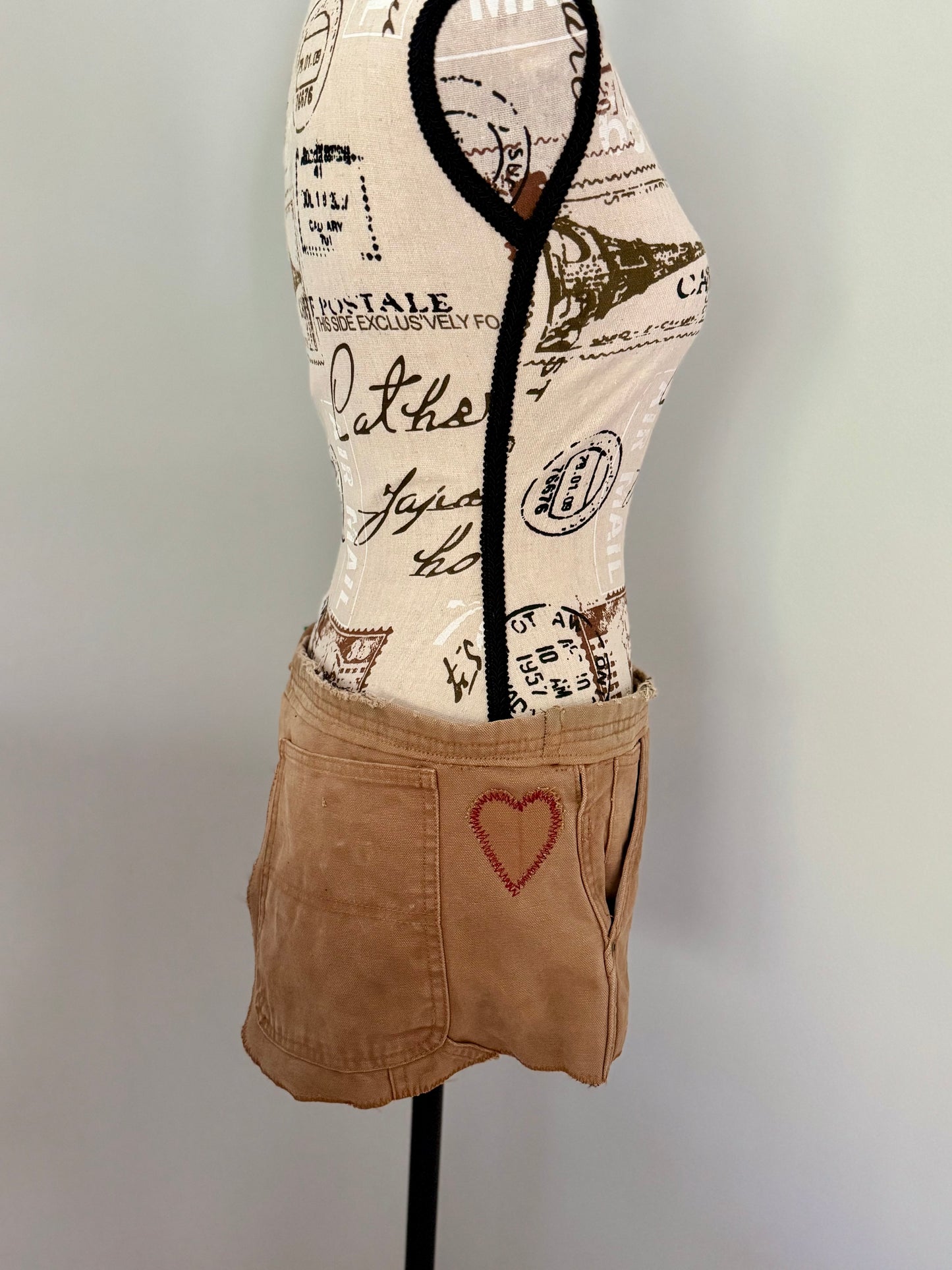 Durable golden brown festival bag repurposed from a pair of bib overalls and features a hand stitched heart patch, original pockets and fasteners. Designed for utility and to carry necessities such as phone, keys, wallet, etc.