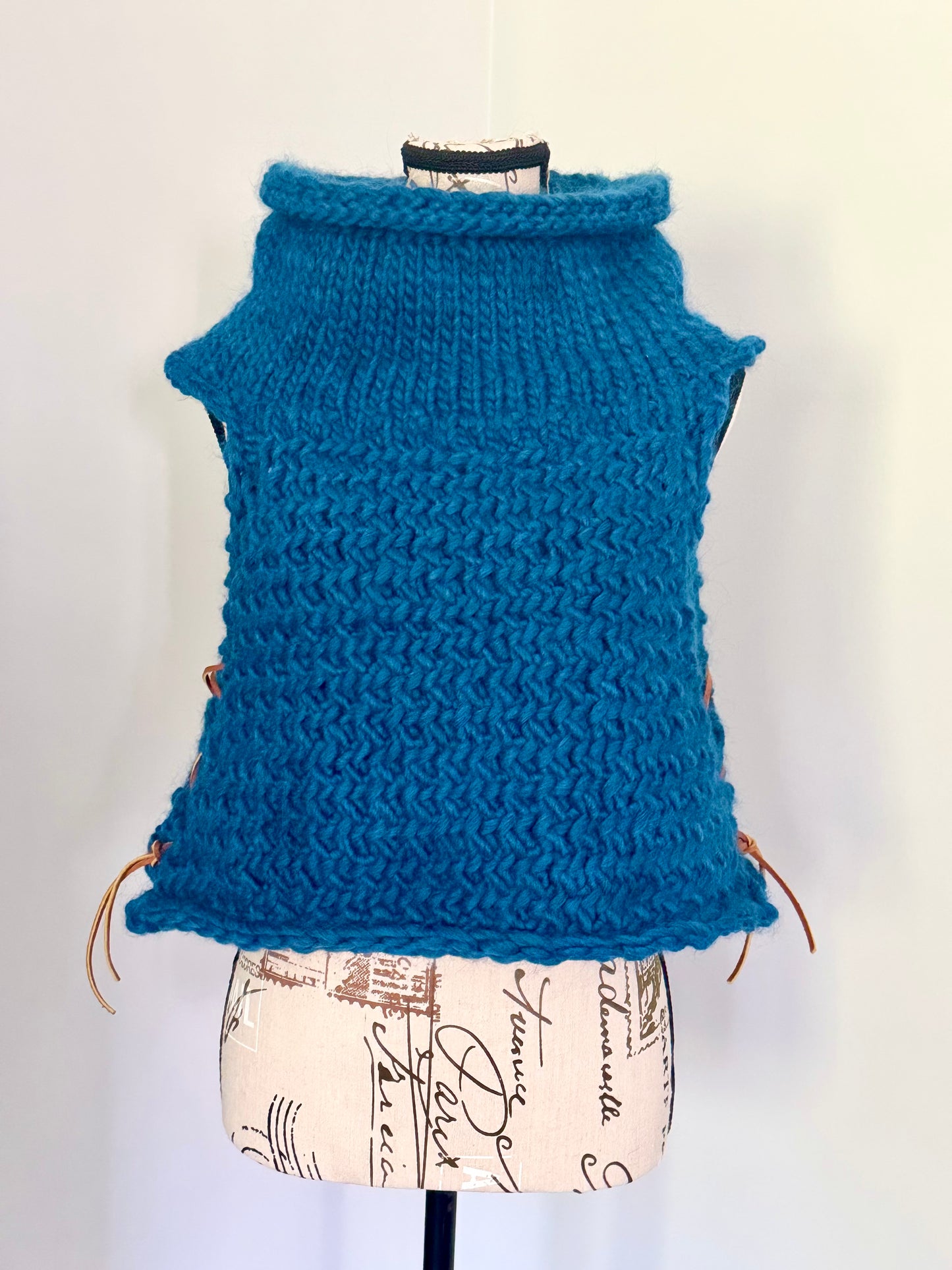 Super bulky and structured hand knitted vest constructed in a herringbone stitch featuring leather lace accents. Custom commission this piece in the color of your choice and in cropped or regular length.