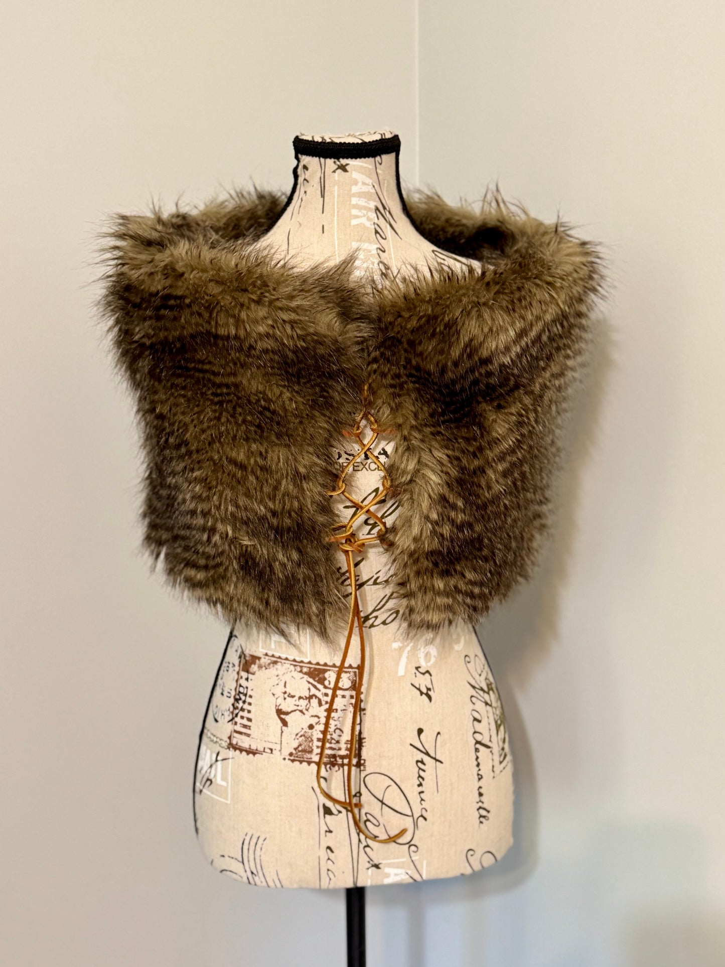 Brown knitted vest with faux fur trim and leather lacing on a mannequin against a plain background
